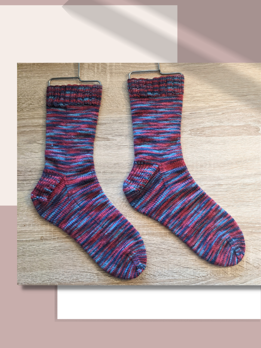 pink blue and purple handknit socks on a light wood background